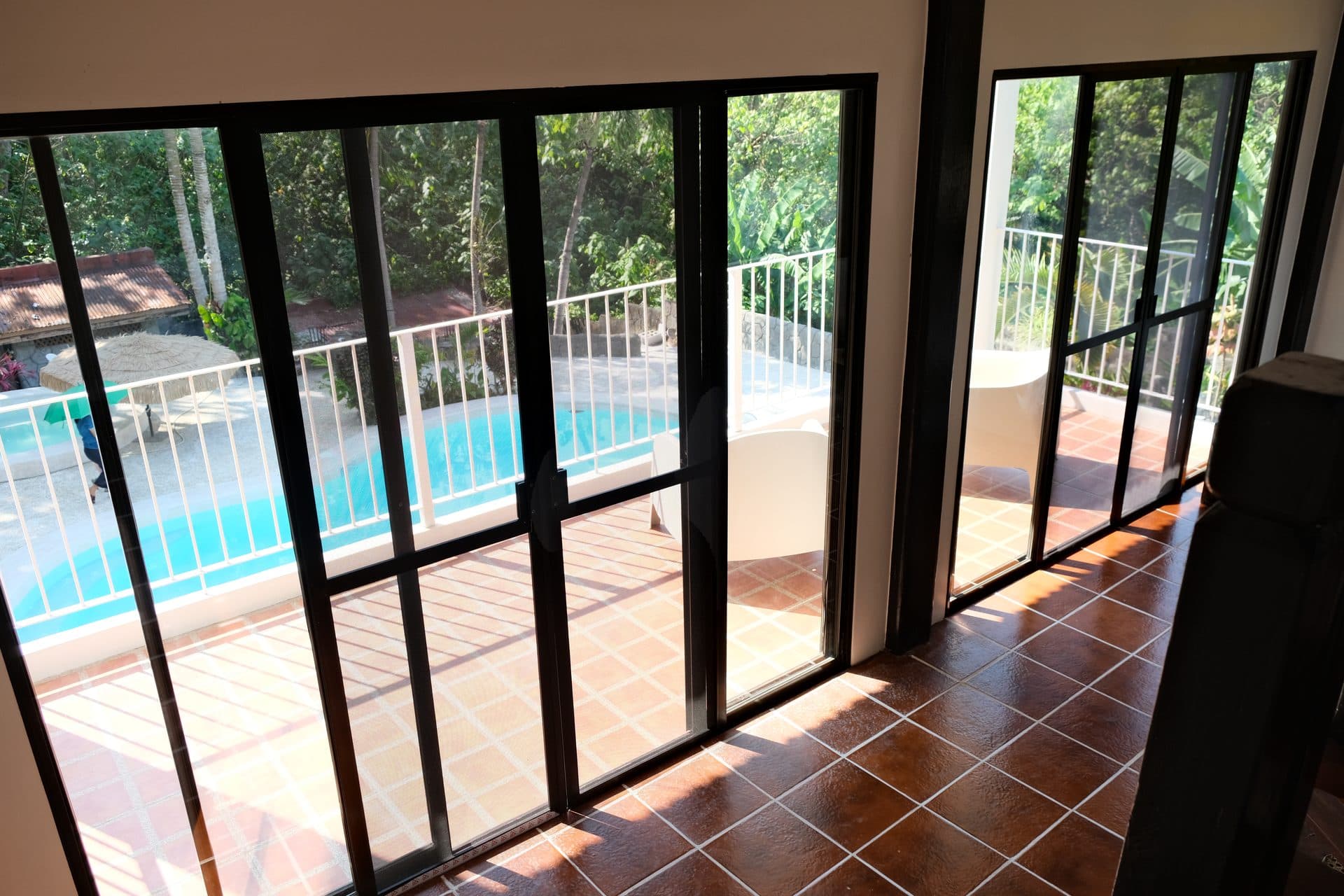 Balay sa Pansol living room with large glass doors opening to pool view and lush greenery